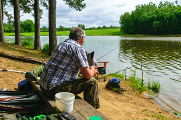 photo from summer with an angler, angler sits on the shore of the lake and catches fish,