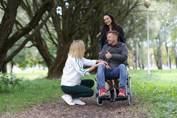 Women friends walking with disabled man in wheelchair in park
