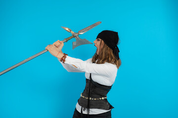Angry young pirate girl holding a spear and screaming on a blue background