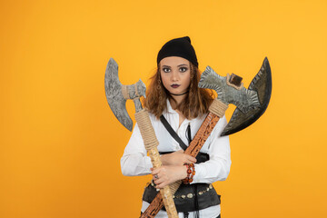 Pretty young girl holding axes and looking at camera