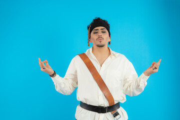 Handsome pirate stands on a blue background and gesture meditation.