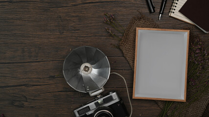 Above view retro camera, empty picture frame and notebook on wooden background