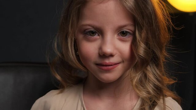 The little girl is surprised. Close-up portrait in the studio on a dark background.