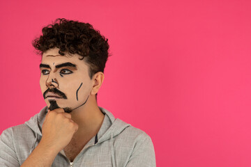 Close-up photo of young man with fantasy makeup stands on red background