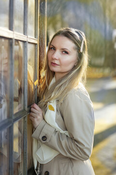 young blond beautiful woman with long hair wearing trench coat closeup street portrait