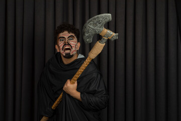 Obraz premium Angry warrior with an ax on black background looking at camera