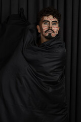 Fototapeta na wymiar Creative young man with black cape on black background
