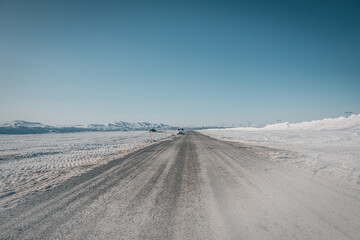 Road trip on Flatruet - Sweden's highest country road to mountain. Winter times on gravel road. Clouds of dust while car passes by rapidly.