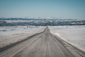 Roadtrip on Flatruet - Sweden's highest backcountry road to mountain. Winter times on gravel road. Endless straight highway to valley. Copy space. Useable as background.