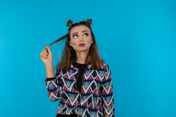 Portrait of attractive girl with creative makeup straighten her hair and stand on blue background