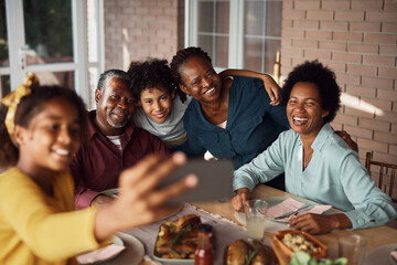 Happy African American extended family having fun while taking selfie during lunch on patio.