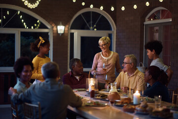 Happy multiracial people enjoying in family gathering at dining table on patio.