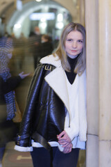 young blond slavic woman with long hair in black leather jacket closeup photo on city undeground station background