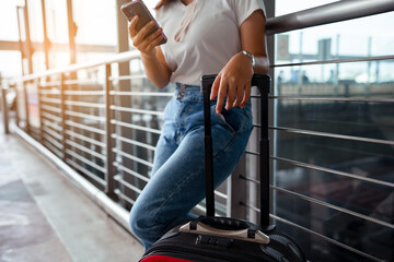 Traveler with suitcase in airport concept.Young girl using smartphone with carrying luggage and passenger for tour travel booking ticket flight at international vacation time in holiday..