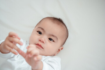 Smiling of newborn baby or cute little lying on a white bed at home. Infant child portrait happy concept, Healthy childcare in the morning.