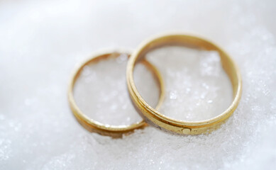 Obraz na płótnie Canvas Gold wedding rings on ice and snow