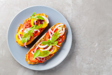 Spanish tapas on concrete. Bruschetta with fresh tomato, greens and olives. Vegetarian sandwiches on a gray plate. Top view. Copy space