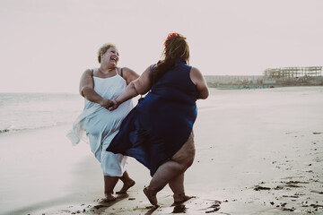 Happy plus size women having fun on the beach during summer vacation 
