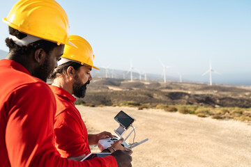 Drone engineers working on wind turbine farm - Alternative energy and aerial engineering concept