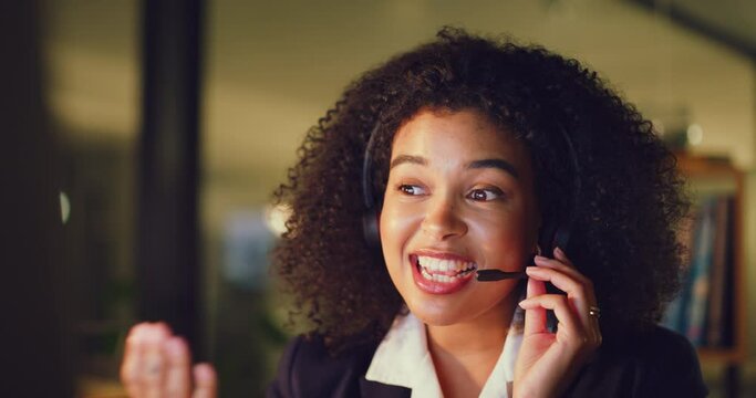 Young female call center agent talking and helping customers while working late in an office alone. One black female virtual helpdesk worker having a conversation with a client and doing overtime