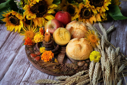 Wiccan Altar for Lammas, Lughnasadh pagan holiday. wheel of the year with ears of wheat, amulet, bread, flowers, apple, candle on dark wooden background. symbol of celtic wiccan sabbath, summer season