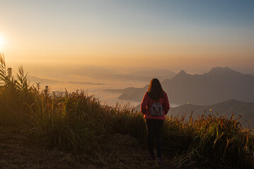Traveler Asian woman enjoying and relaxing on the mountains view containing calm, fog, and mist in the morning.

