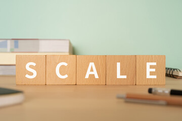 規模・尺度のイメージ｜「SCALE」と書かれたブロックが置かれたデスク
