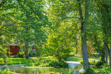Red cottage by a pond in a lush green deciduous forest