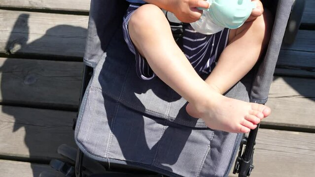 Bare feet of a baby in a stroller on a sunny summer day