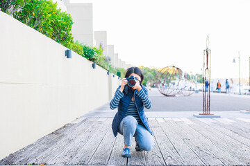 しゃがんで写真を撮る女性フォトグラファー