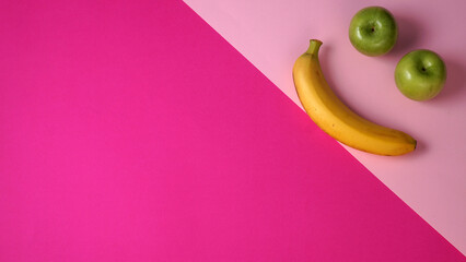 Top view of two green apples and a banana arranged in a shape of a smiling face. Duotone background...