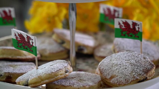 Closeup of traditional Welsh cakes with Welsh flag in panning shot.