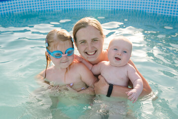 Family playing in the swimming pool. Mother and kids having fun in the pool. Summer leisure and...