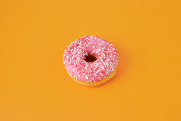 Fototapeta na wymiar pink glazed donut on orange background