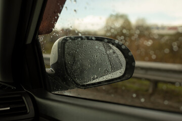 Rear-view mirror in car. Car window in rain. Transport details.