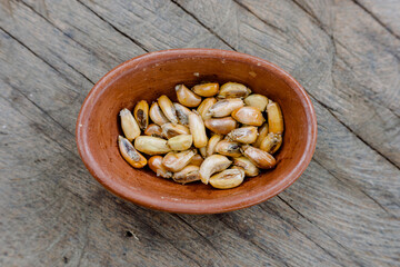 Toasted Andean corn with salt served on a rustic bowl, on a wooden table. Top view. Peruvian food