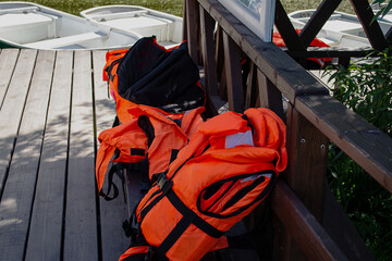 Bright orange life jackets lie on a bench at the boat station. Means of protection, rescue, safety.