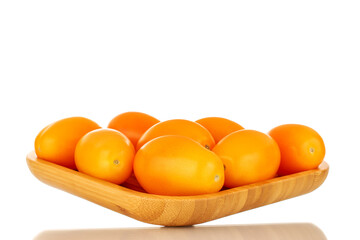 Several ripe yellow tomatoes on a bamboo plate, close-up, isolated on a white background.