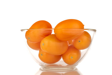 Several ripe yellow tomatoes in a glass plate, close-up, isolated on a white background.