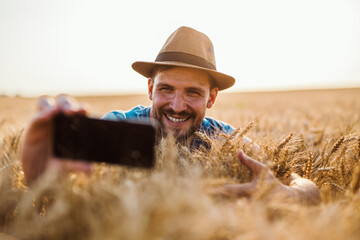 Young farmer taking selfie photo in wheat field.