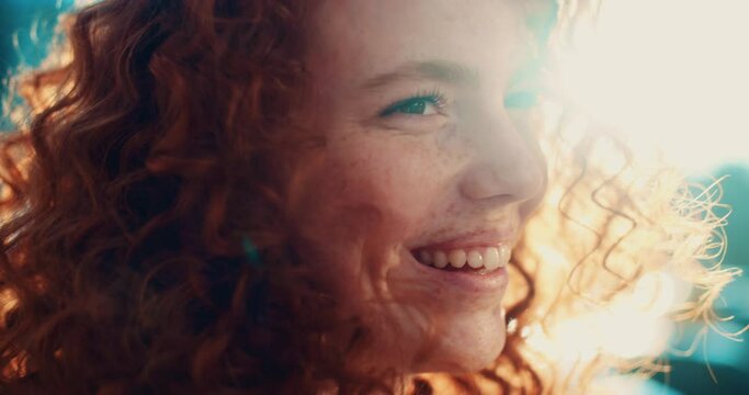Smiling young sunshine woman with red hair turning looking away standing in the city streets. Beautiful town at sunlight. Feel happy. Slow motion