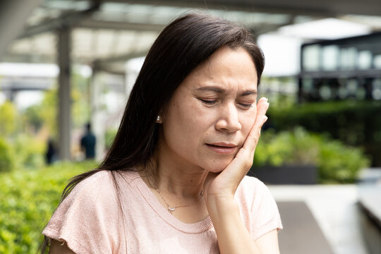 Asian middle aged woman suffering from toothache, tooth decay, tooth sensitivity, oral care concept