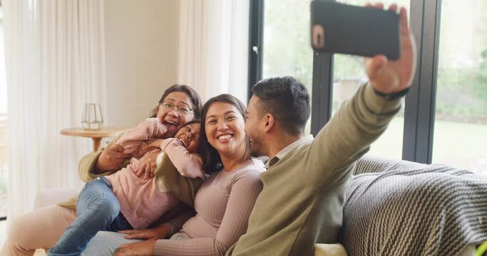 Playful multi generation family taking selfies, bonding at home. Man using a phone to take pictures while taking his little girl to visit her grandmother. Child bonding with her parents