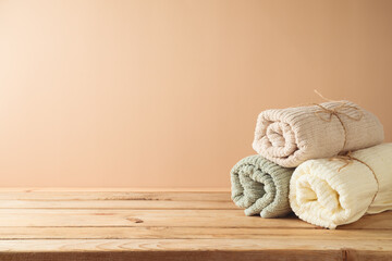 Fresh towels on wooden table over beige background. Bathroom mock up for design and product display