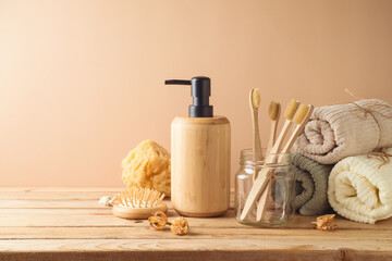 Eco friendly toothbrush, towel and body care products on wooden table over beige background