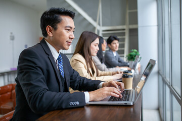 Portrait of Asian middle age businessman working at the office, smile businessman using computer on table