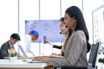 female operator agent with headsets and her team working in a call center customer service office. Asian employee woman working with a headset, Customer support.