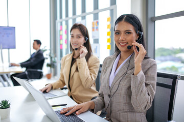 female operator agent with headsets and her team working in a call center customer service office. Asian employee woman working with a headset, Customer support.