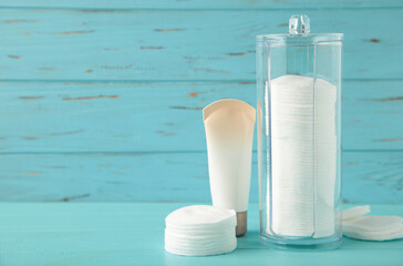 Cream package with cotton pads in container on blue background. Beauty skincare products.