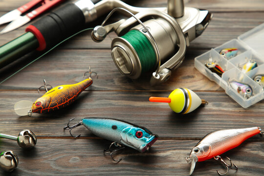 Fishing rods and spinnings in the composition with accessories for fishing on old brown background.